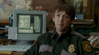 Movie still from “Slither” (2006), directed by James Gunn – A police officer sitting in front of a computer monitor; Close Up shot, Over the shoulder angle