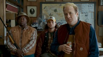 Movie still from “Slither” (2006), directed by James Gunn – A group of men standing next to each other holding drinks; Medium shot, Over the shoulder angle
