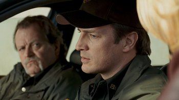 Movie still from “Slither” (2006), directed by James Gunn – A man in a hat sitting in a car; Close Up shot, Over the shoulder angle