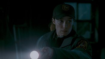 Movie still from “Slither” (2006), directed by James Gunn – A woman holding a flashlight in the dark; Close Up shot, Over the shoulder angle