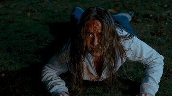 Movie still from “Slither” (2006), directed by James Gunn – A woman laying on the ground covered in blood; Medium shot, High angle