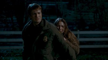 Movie still from “Slither” (2006), directed by James Gunn – A man and a woman are standing next to each other in the dark; Medium shot, Over the shoulder angle