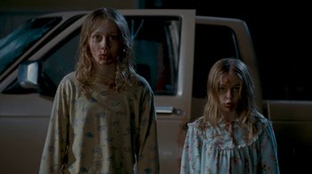 Movie still from “Slither” (2006), directed by James Gunn – Two young girls in pajamas standing in front of a car; Medium shot, Low angle