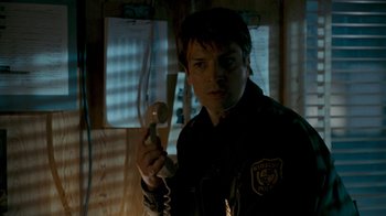 Movie still from “Slither” (2006), directed by James Gunn – A person holding a phone in a dark room; Close Up shot, Over the shoulder angle