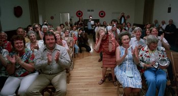 Movie still from “Smile” (1975), directed by Michael Ritchie – A group of people sitting in a room clapping; Wide shot, High angle