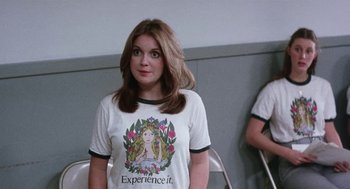 Movie still from “Smile” (1975), directed by Michael Ritchie – A woman in a t - shirt is standing in front of a wall; Medium shot, Over the shoulder angle