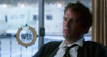 Movie still from “Smile” (1975), directed by Michael Ritchie – A man in a suit and tie sitting in front of a window; Close Up shot, Low angle
