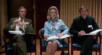 Movie still from “Smile” (1975), directed by Michael Ritchie – A woman sitting in a chair in front of two other people; Medium shot, High angle