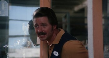 Movie still from “Smile” (1975), directed by Michael Ritchie – A man with a mustache standing in front of a window; Close Up shot, Over the shoulder angle