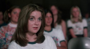 Movie still from “Smile” (1975), directed by Michael Ritchie – A woman in white shirt looking at the camera; Close Up shot, Over the shoulder angle