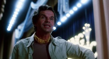 Movie still from “Smile” (1975), directed by Michael Ritchie – An older man with long hair wearing a white shirt and a yellow neck tie; Close Up shot, Low angle