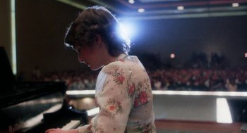 Movie still from “Smile” (1975), directed by Michael Ritchie – A woman in a floral dress is playing the piano; Medium shot, Over the shoulder angle