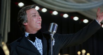 Movie still from “Smile” (1975), directed by Michael Ritchie – A man in a tuxedo is singing into a microphone; Close Up shot, Low angle