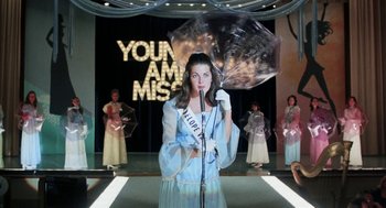 Movie still from “Smile” (1975), directed by Michael Ritchie – A woman holding an umbrella while standing on a stage; Medium shot, Low angle