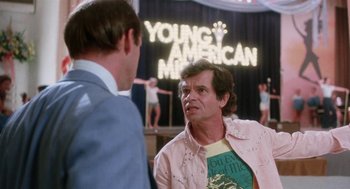 Movie still from “Smile” (1975), directed by Michael Ritchie – Two men are talking in front of a young american music sign; Medium shot, Over the shoulder angle