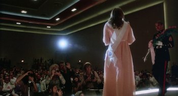 Movie still from “Smile” (1975), directed by Michael Ritchie – A woman wearing a pink dress and a white sash; Wide shot, Low angle