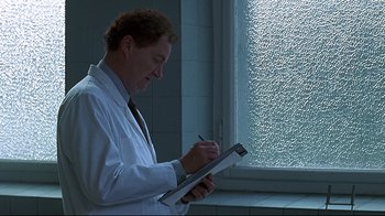 Movie still from “Smilla's Sense of Snow” (1997), directed by Bille August – A man in white lab coat writing on a piece of paper; Medium shot, Low angle