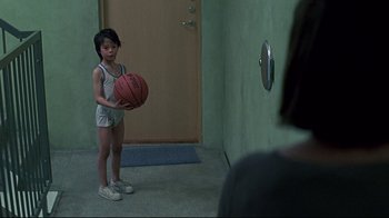 Movie still from “Smilla's Sense of Snow” (1997), directed by Bille August – A young girl holding a basketball in front of a door; Wide shot, Over the shoulder angle