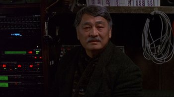 Movie still from “Smilla's Sense of Snow” (1997), directed by Bille August – An older asian man in a black jacket; Close Up shot, Low angle