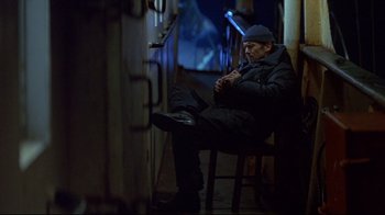 Movie still from “Smilla's Sense of Snow” (1997), directed by Bille August – A man sitting on a chair in a dark room; Wide shot, High angle