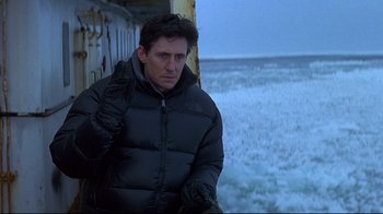 Movie still from “Smilla's Sense of Snow” (1997), directed by Bille August – A man in a black jacket standing next to the ocean; Medium shot, Over the shoulder angle