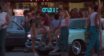 Movie still from “Smooth Talk” (1985), directed by Joyce Chopra – A group of people standing on the hood of an old car; Wide shot, High angle