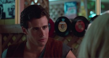 Movie still from “Smooth Talk” (1985), directed by Joyce Chopra – A man sitting in front of some records; Close Up shot, Over the shoulder angle