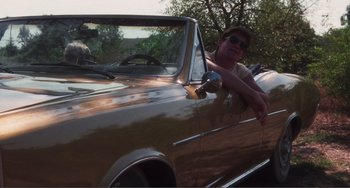 Movie still from “Smooth Talk” (1985), directed by Joyce Chopra – A man sitting in the driver's seat of an old car; Wide shot, Low angle