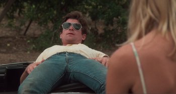Movie still from “Smooth Talk” (1985), directed by Joyce Chopra – A man wearing sunglasses sitting on top of a car; Medium shot, Low angle