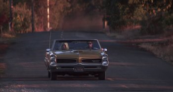 Movie still from “Smooth Talk” (1985), directed by Joyce Chopra – A man and a woman driving a car down a street; Wide shot, High angle
