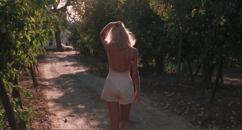 Movie still from “Smooth Talk” (1985), directed by Joyce Chopra – A woman walking down a dirt road in a white dress; Wide shot, High angle
