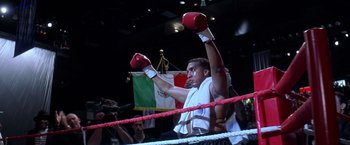 Movie still from “Snake Eyes” (1998), directed by Brian De Palma – A man in a boxing ring raising his hands; Medium shot, Low angle