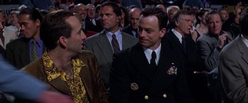 Movie still from “Snake Eyes” (1998), directed by Brian De Palma – A group of men in suits and ties in front of a crowd; Medium shot, Over the shoulder angle