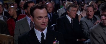 Movie still from “Snake Eyes” (1998), directed by Brian De Palma – A man in a suit and tie in front of a crowd; Close Up shot, Over the shoulder angle