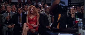 Movie still from “Snake Eyes” (1998), directed by Brian De Palma – A woman in a red dress sitting next to a man in a black suit; Medium shot, Over the shoulder angle