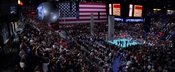 Movie still from “Snake Eyes” (1998), directed by Brian De Palma – A crowd of people in front of an american flag; Extreme Wide shot, High angle