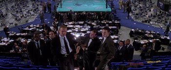 Movie still from “Snake Eyes” (1998), directed by Brian De Palma – A group of men standing in front of a boxing ring; Wide shot, High angle