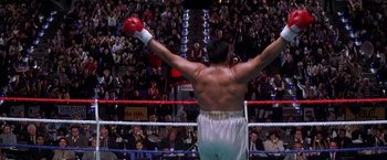 Movie still from “Snake Eyes” (1998), directed by Brian De Palma – A man in a boxing ring with his hands raised; Wide shot, Low angle
