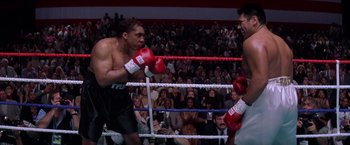 Movie still from “Snake Eyes” (1998), directed by Brian De Palma – Two boxers in a boxing ring during an event; Medium shot, High angle