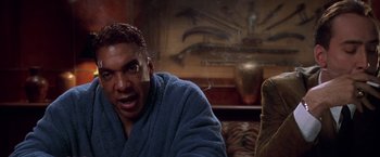 Movie still from “Snake Eyes” (1998), directed by Brian De Palma – A man in a blue bathrobe is looking at the camera; Close Up shot, Low angle