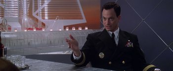 Movie still from “Snake Eyes” (1998), directed by Brian De Palma – A man in a uniform sitting at a table; Medium shot, Low angle