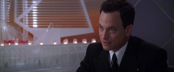 Movie still from “Snake Eyes” (1998), directed by Brian De Palma – A man in a suit and tie sitting at a table; Close Up shot, Low angle