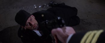 Movie still from “Snake Eyes” (1998), directed by Brian De Palma – A man laying on the ground with a gun pointed at him; Close Up shot, Overhead angle
