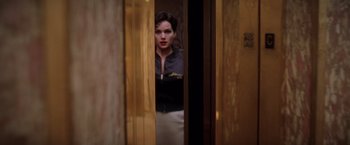 Movie still from “Snake Eyes” (1998), directed by Brian De Palma – A woman standing in front of a door looking at the camera; Medium shot, Low angle