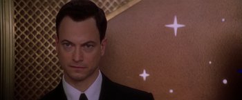 Movie still from “Snake Eyes” (1998), directed by Brian De Palma – A man in a suit and tie standing in front of a wall; Close Up shot, Low angle