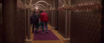 Movie still from “Snake Eyes” (1998), directed by Brian De Palma – Two people are walking down the hallway of a building; Wide shot, High angle