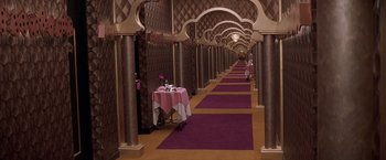 Movie still from “Snake Eyes” (1998), directed by Brian De Palma – A long hallway with purple carpet and a table with a pink table cloth on it; Extreme Wide shot, High angle