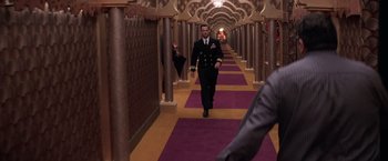 Movie still from “Snake Eyes” (1998), directed by Brian De Palma – A man walking down a long hallway in a hotel; Wide shot, Over the shoulder angle