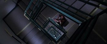 Movie still from “Snake Eyes” (1998), directed by Brian De Palma – A man sitting on the ground on the stairs of a building; Extreme Wide shot, Overhead angle