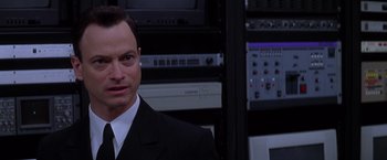 Movie still from “Snake Eyes” (1998), directed by Brian De Palma – A man in a suit and tie in a room; Close Up shot, Low angle